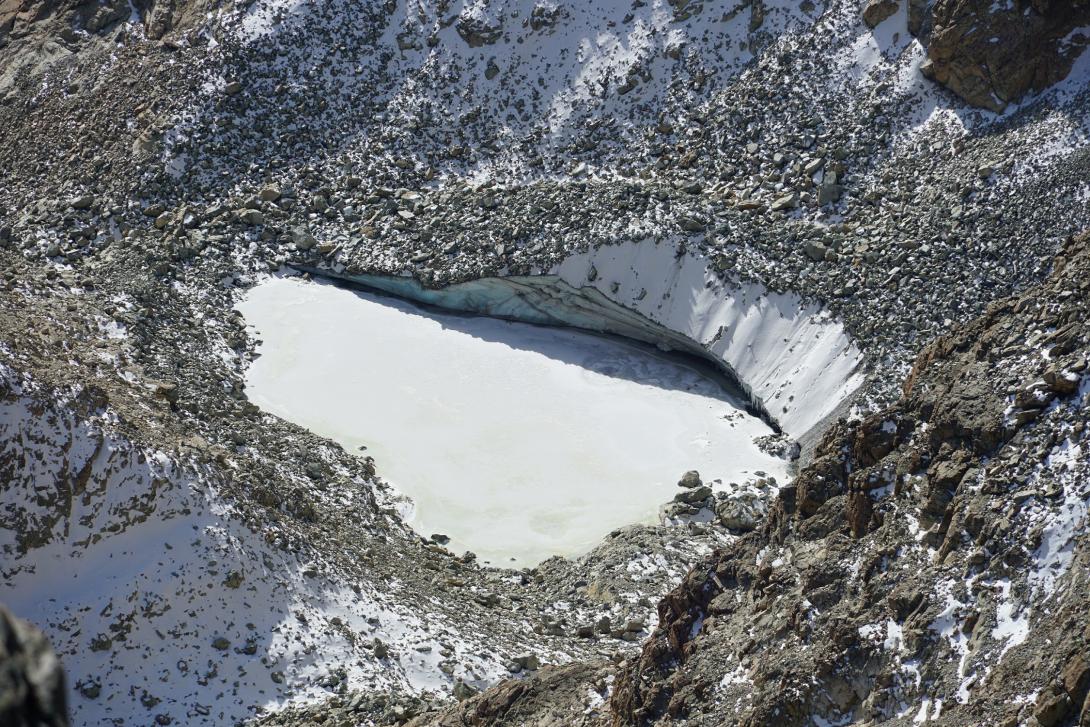 Lago glaciale nella conca sottostante la Punta Fiume, ricoperto da un leggero velo di neve fresca; fotografia scattata dalla punta del Monviso (29 ottobre 2022)
